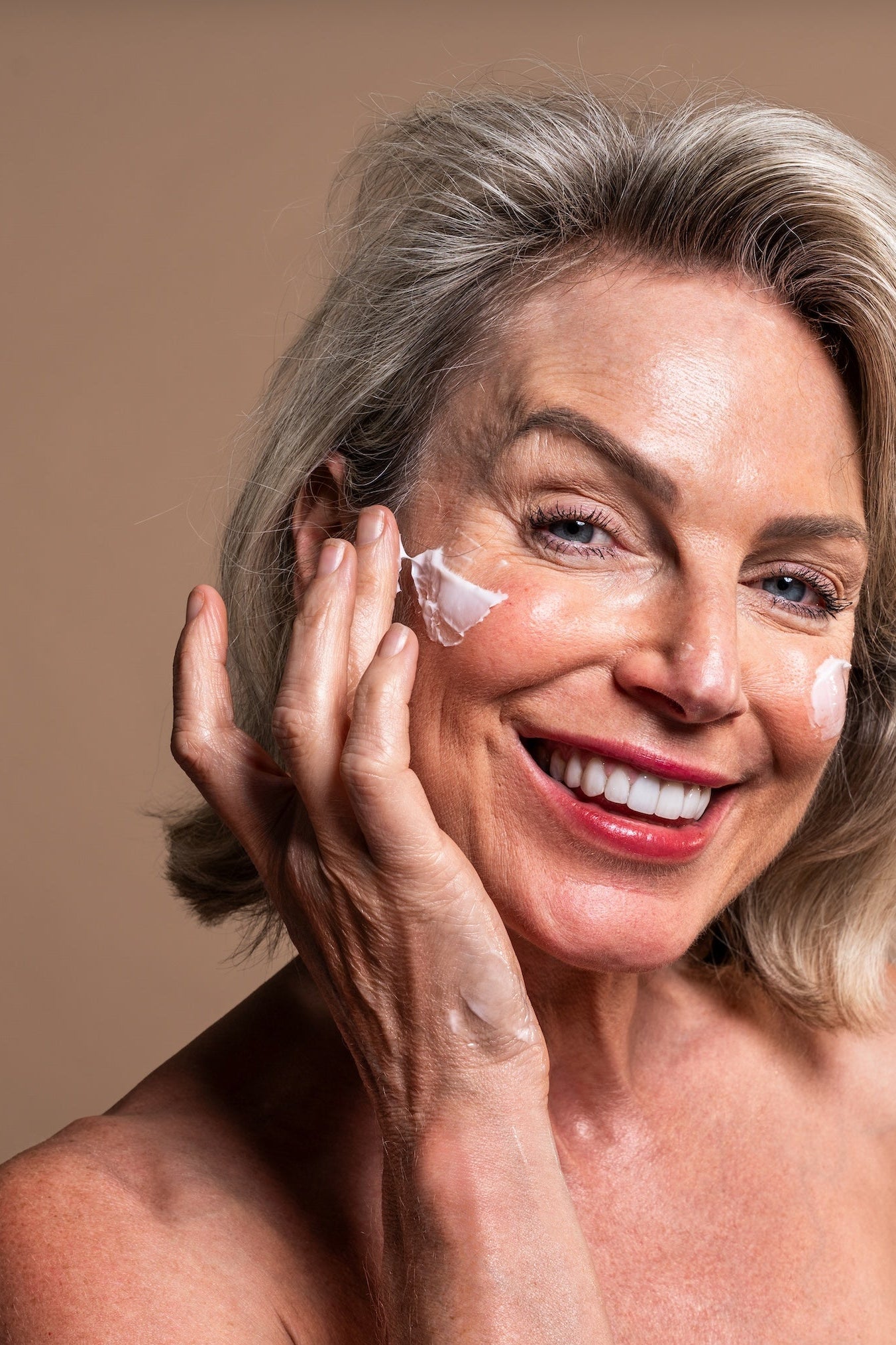Middle-aged woman applying skin cream to her face 